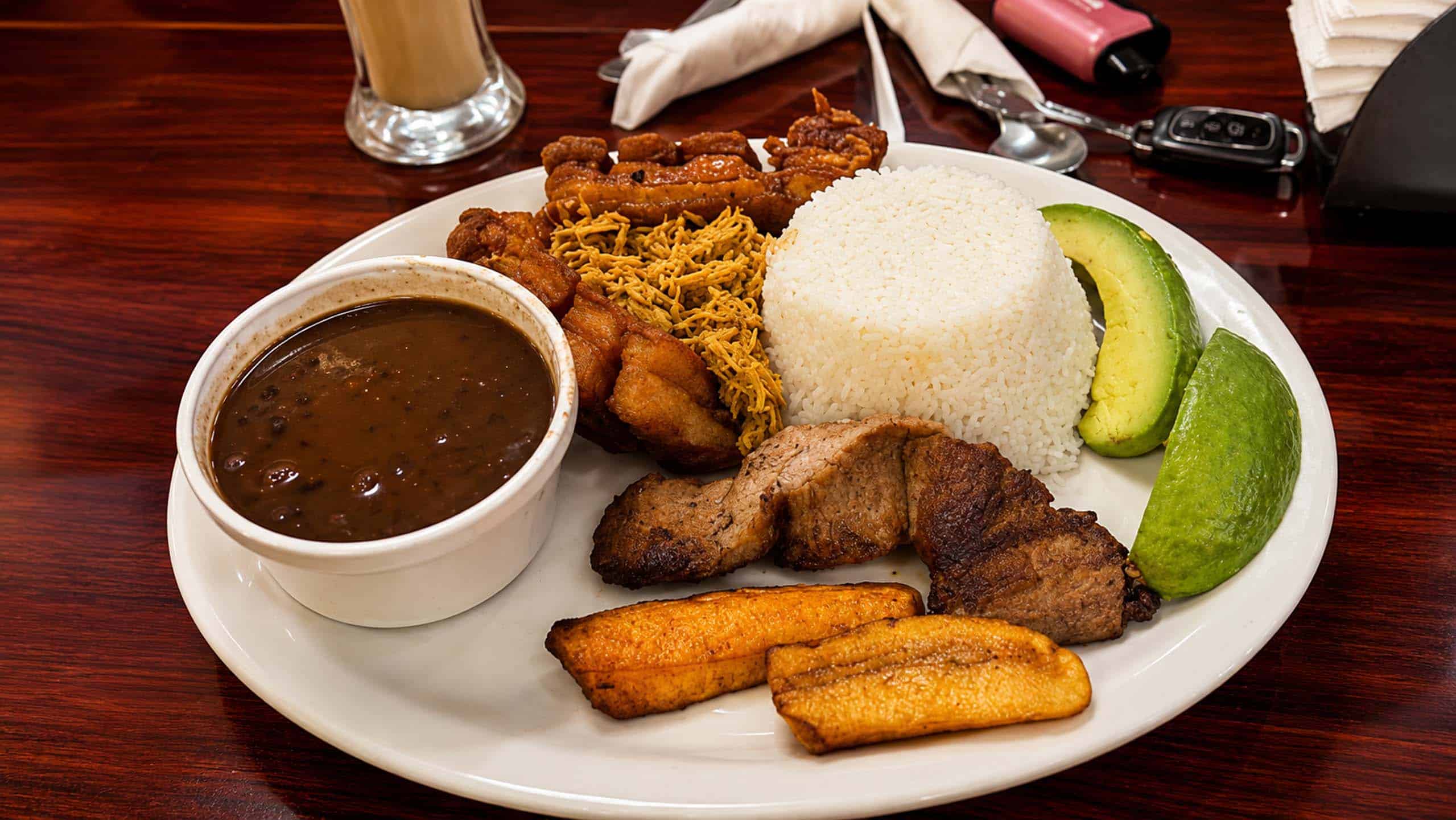 Bandeja Paisa with black beans, rice, pork, plantain, avocado and lime